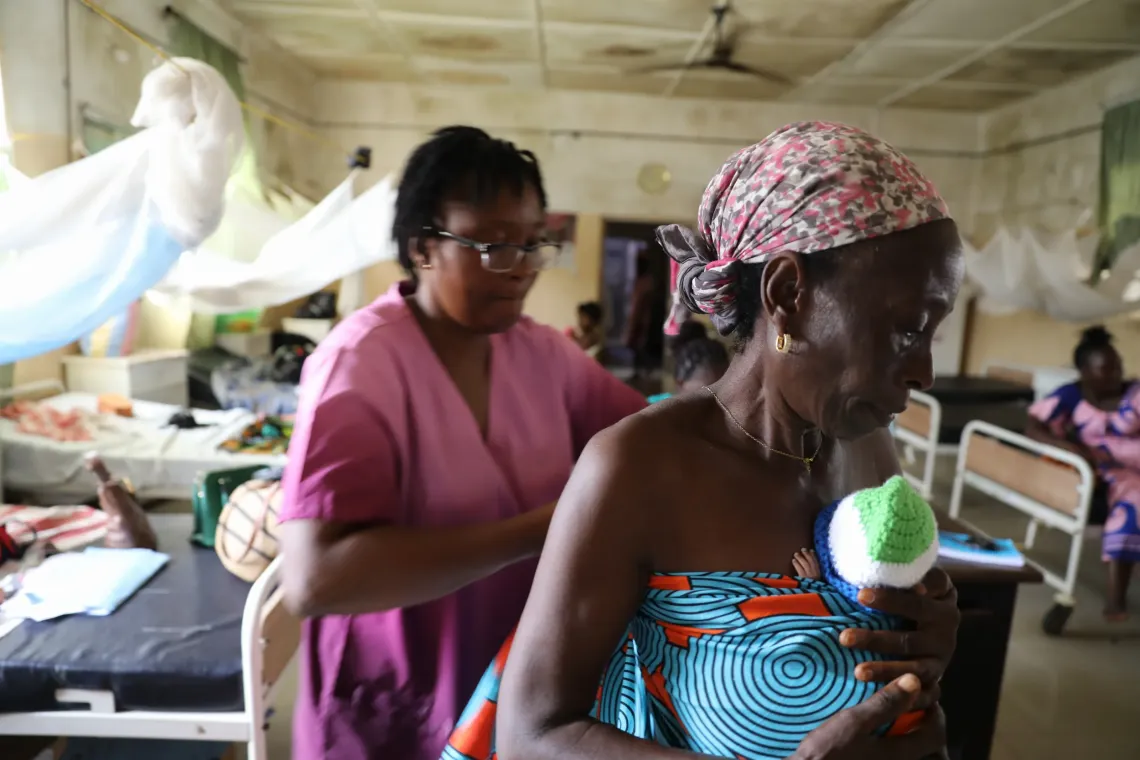 Grandmother, Hawa George, receives additional support on Kangaroo Mothers Care practice from another nurse at the Special Care Baby Unit, Bo Government Hospital