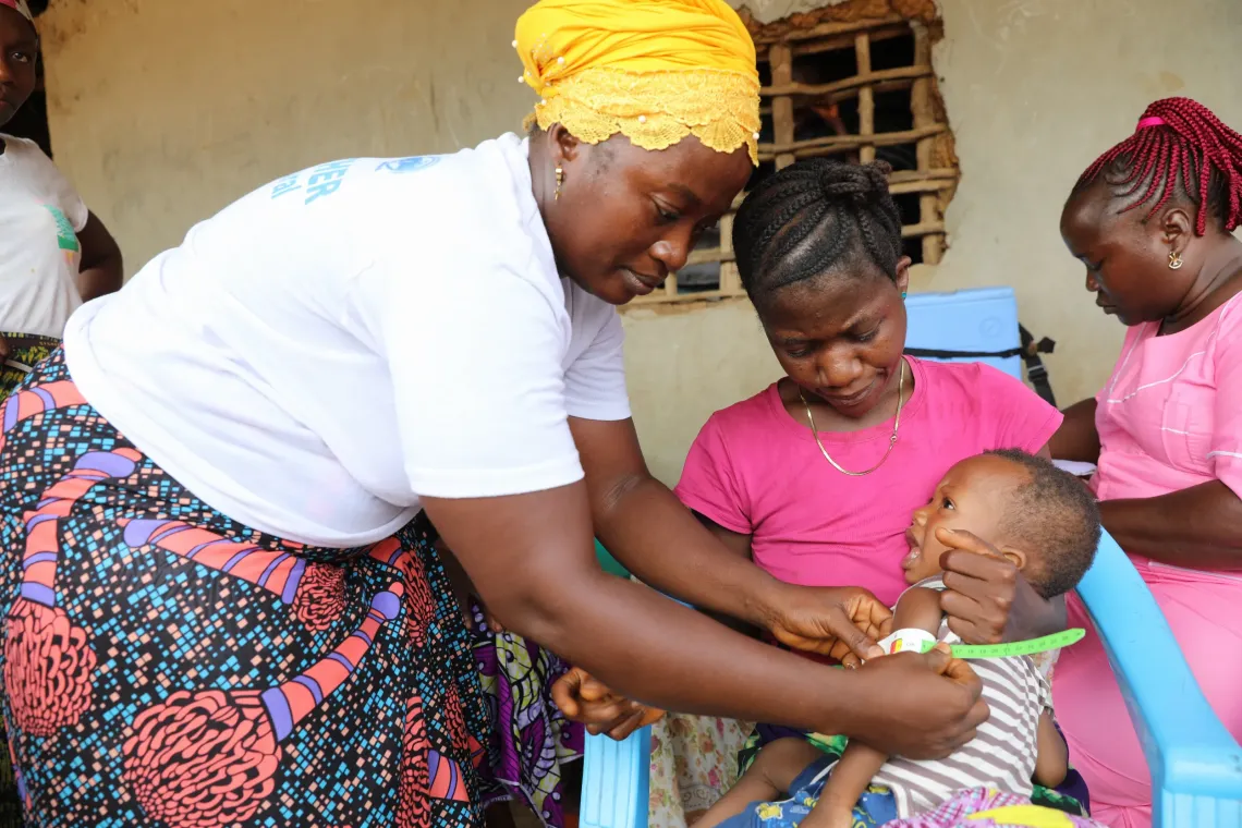 Isatu Fullah, a Mothers Support Group member in Njagbahun village, Moyamba District, screens a one-year-old child for malnutrition using a Mid Upper Arm Circumference (MUAC) tape