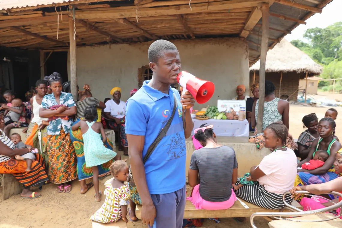 Mohamed Kamara, a Community Health Worker (CHW), mobilizes mothers with under-five children for a community outreach session in Njagbahun village, Moyamba, District