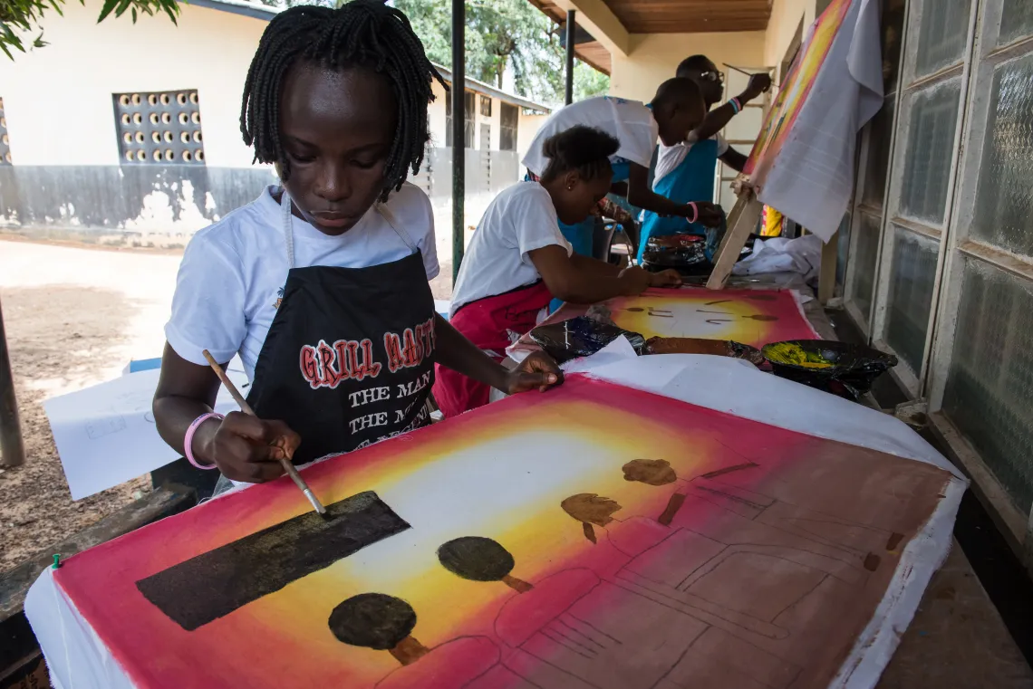 15-year-old Kadiatu Kainessie works on a painting of children in a classroom, during an art session in Bo, southern Sierra Leone.