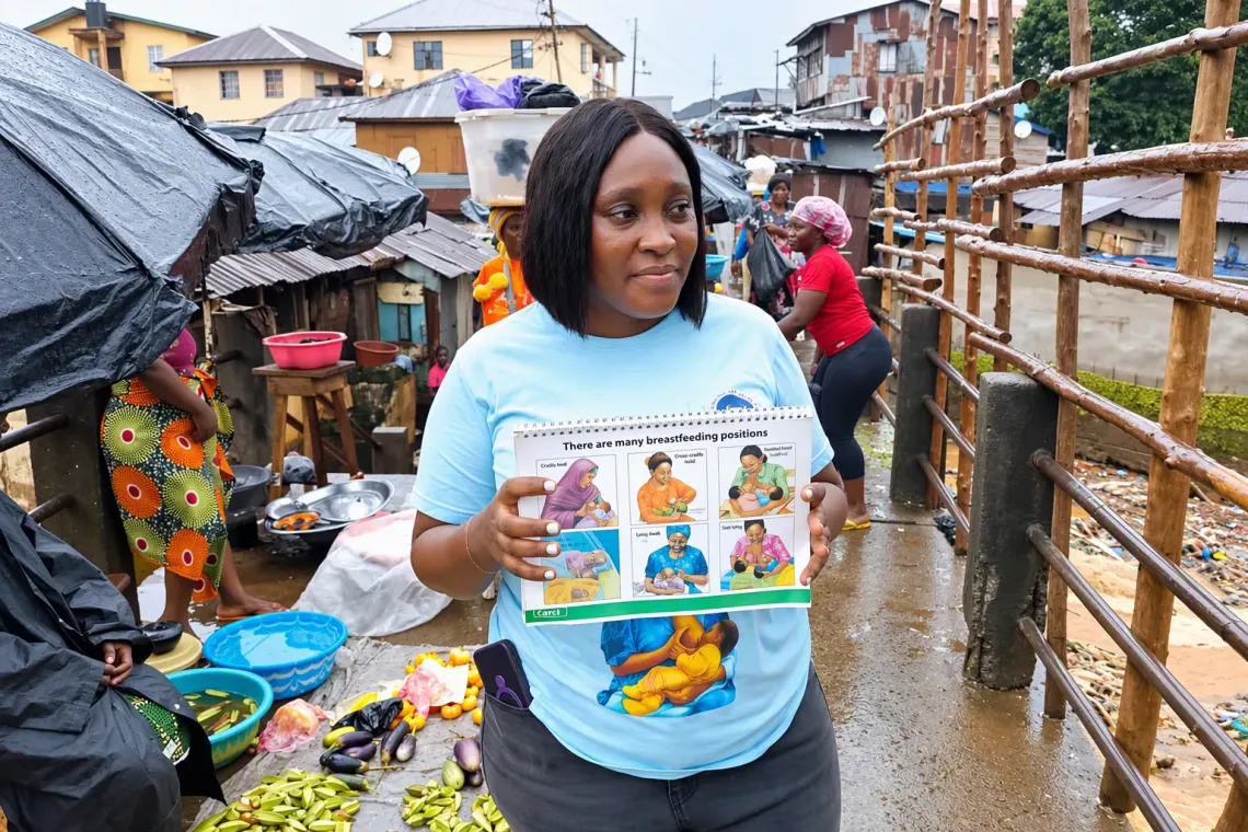 Health worker, Mantina, displays an illustrated booklet on recommended breastfeeding practices to market women and shoppers at the Congo Market in Freetown during the World Breastfeeding Week 