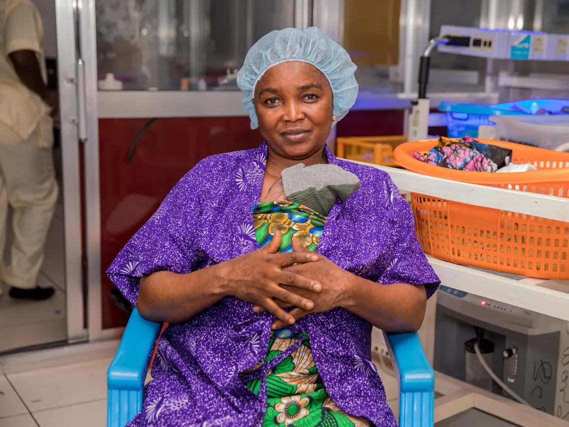 Zainab Manasary holds her granddaughter close to her chest while practising Kangaroo Mother Care at the Special Care Baby Unit of Makeni Government Hospital, Sierra Leone. The nurses introduced her to the practice while the baby&rsquo;s mother recovered from a Caesarean section. &copy; UNICEF/Islander Kabia