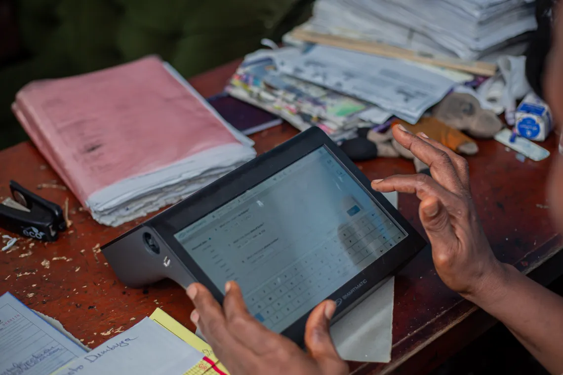 Someone partially visible holds a computer tablet.