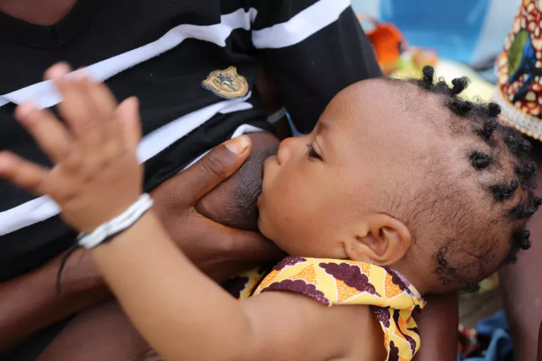 A woman breastfeeds her child at a marketplace in Moyamba district, southern Sierra Leone.