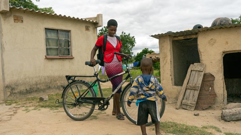 mother-on-bicycle-outside-house