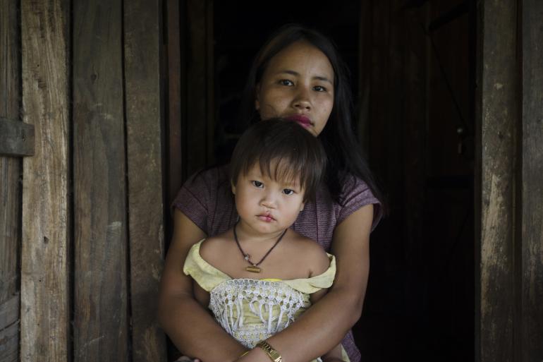 On 19 September 2022 in Khamblaiglat village, Anjaw district of Arunachal Pradesh state, India, mother Atyula Khamlai, 24, sits with her 3-year-old daughter on her lap during Village Health and Nutrition Day, an immunization and health outreach campaign.