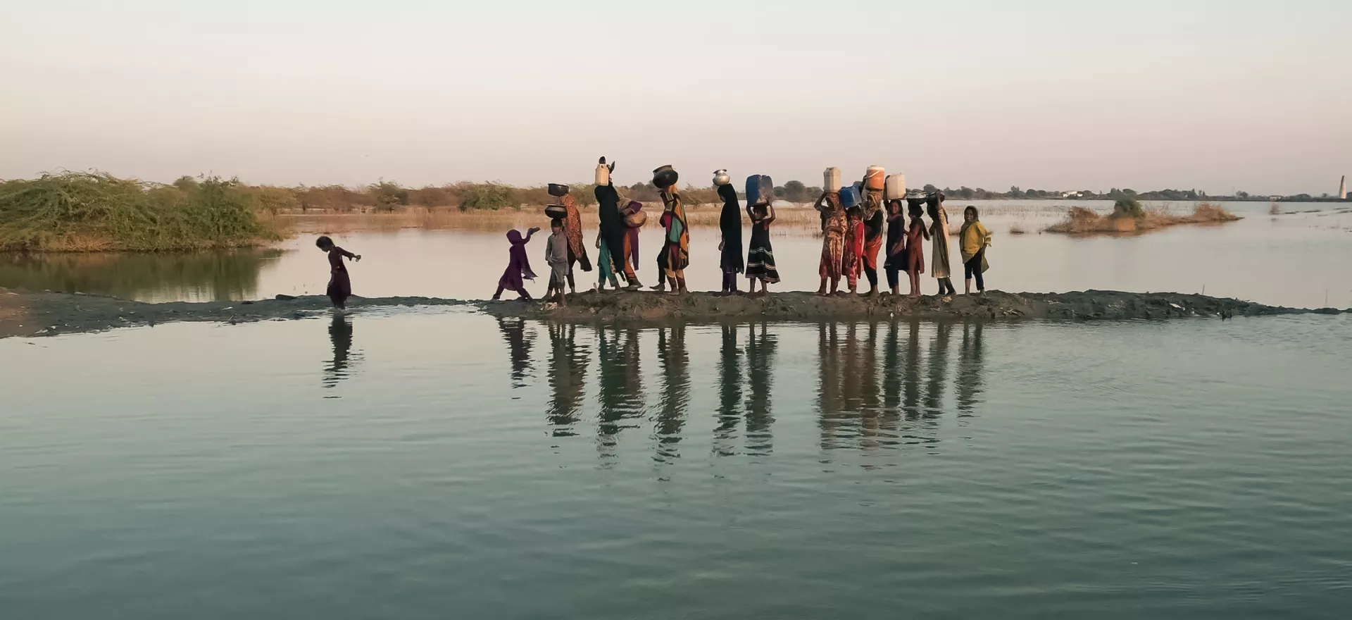 Women and girls walking with their buckets to fetch water in the inundated region of Geokaloi village in the Southern Pakistani province of Sindh.