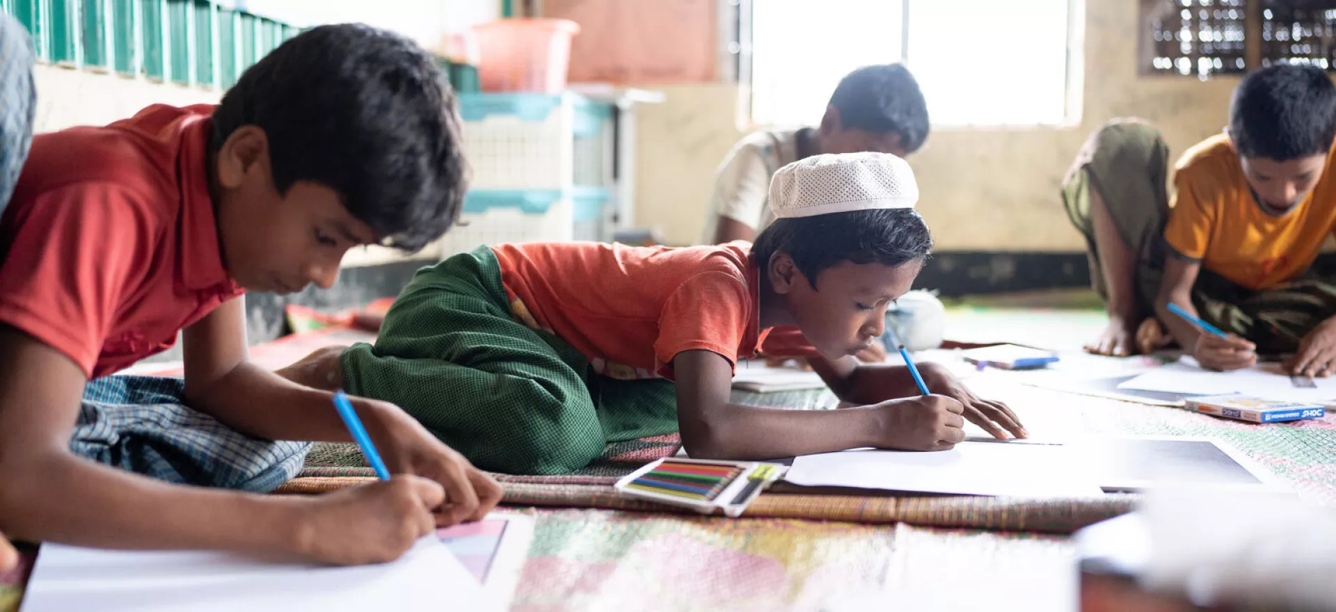 Bangladesh. A group of children draw pictures with colouring pencils during a group activity session at a Multi-Purpose Centre in a Rohingya refugee camp in Cox&rsquo;s Bazar