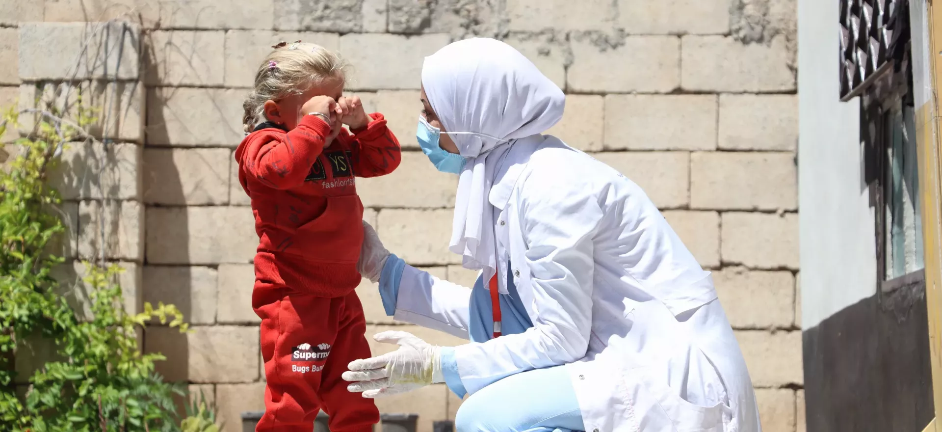 Syria. A nutrition nurse kneels down to speak with a child.