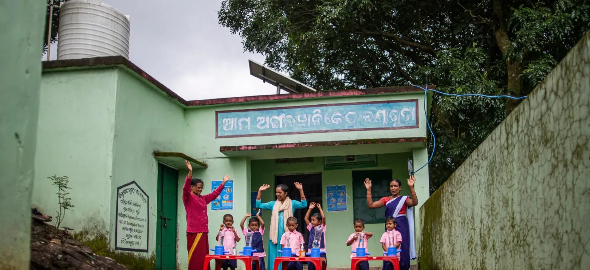 Women standing behind children in front of school