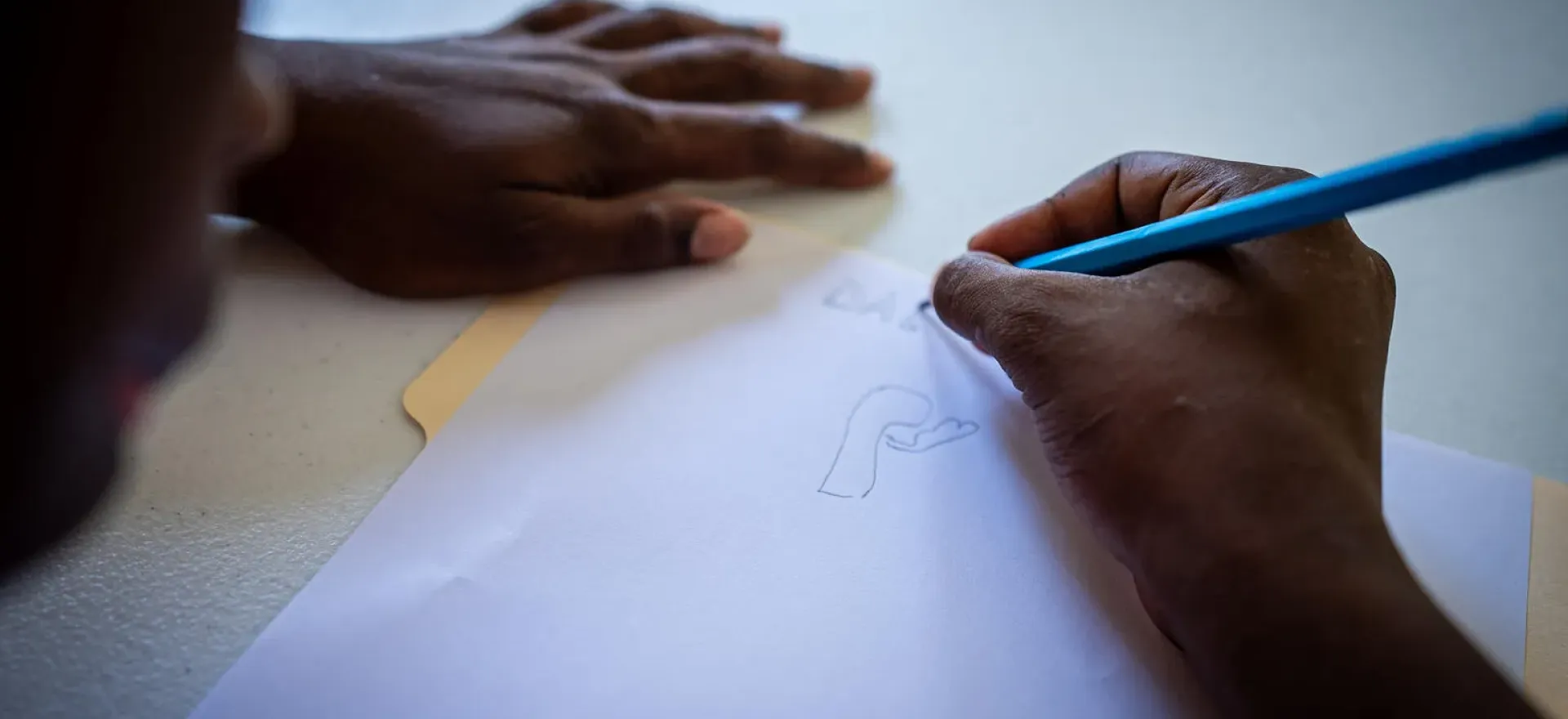 Haiti. A boy draws at a transit centre.