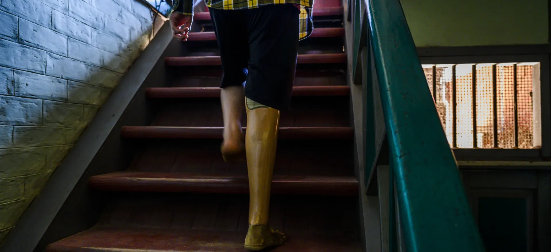 Myanmar. Saw Ler is pictured walking up some steps wearing his prosthetic leg.