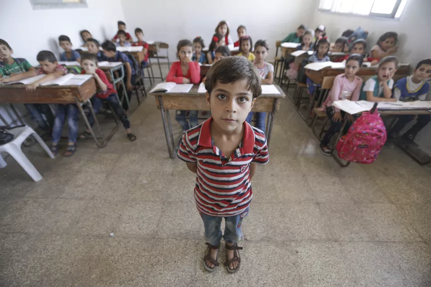 A boy stands in the front of a classroom, Syrian Arab Republic