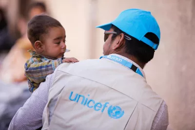 Un trabajador de UNICEF lleva en brazos a un beb&eacute;