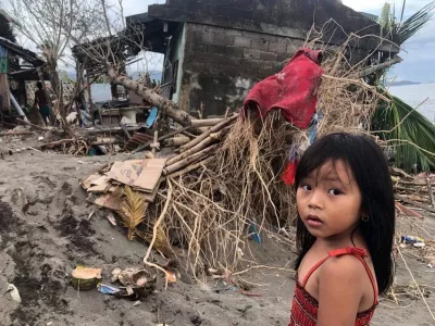 Philippines. A child stands by her destroyed home following Typhoon Rolly.