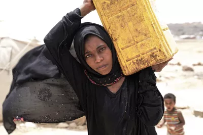 Yemen. Una mujer lleva un recipiente de agua.