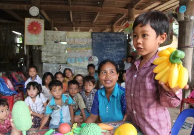 Un enfant tient des bananes en plastique pendant une leçon dans un établissement préscolaire