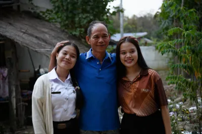 Sisters Kanokwan and Kamonwan Nongyaw embrace their father outside their family home.