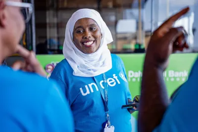 A UNICEF health specialist smiles while speaking with colleagues.