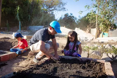 UNICEF personnel helps girl plant a lettuce in the community garden of the Municipality of Guatemala.