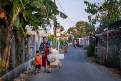  A woman walks hand in hand with a child carrying water along a bustling street.
