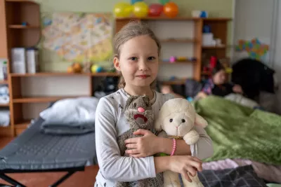 Eight-year-old Alyona cradles her cherished toys, including Motya, her grey rabbit, and a white lamb. 