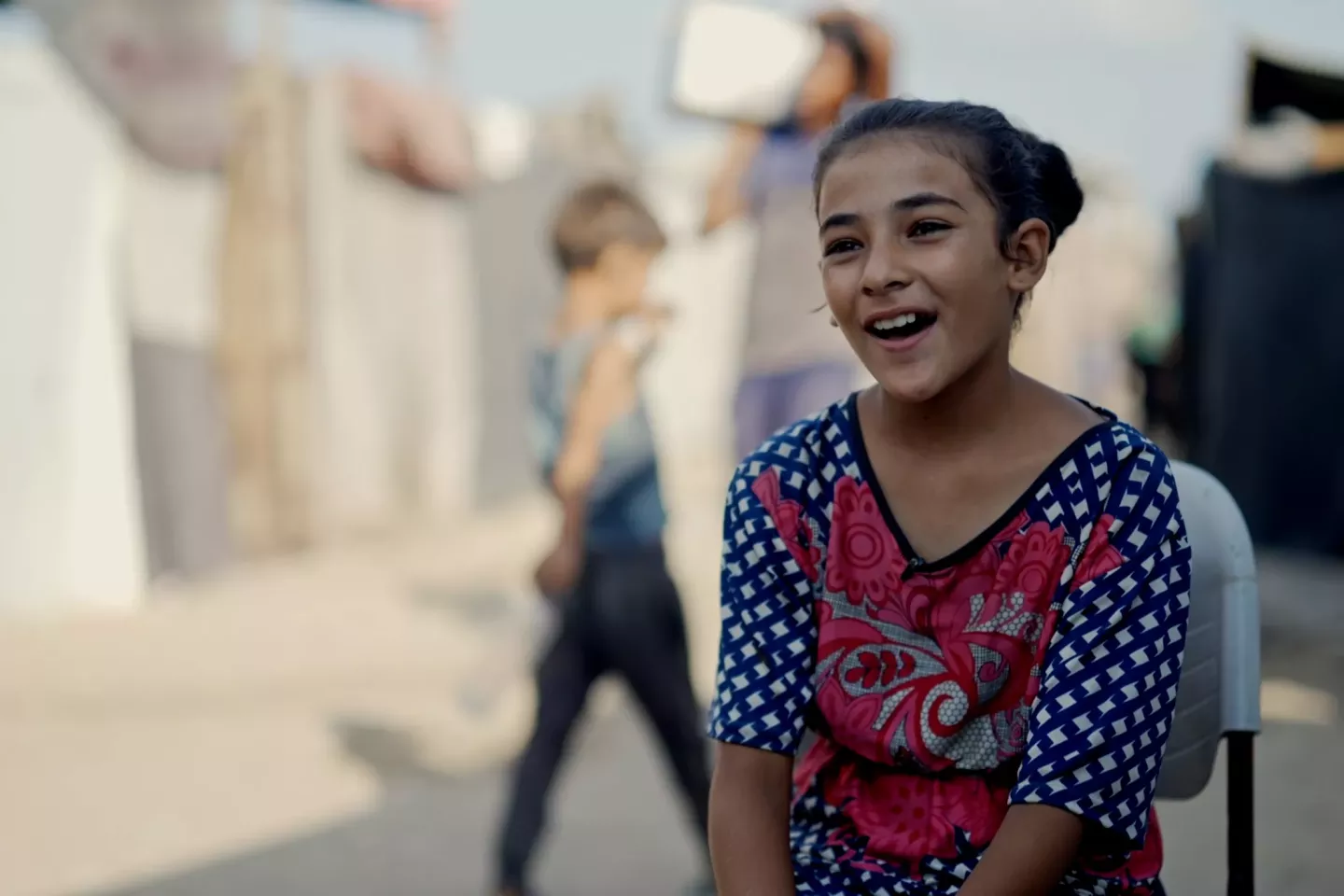 Gaza Strip. A girls sits and talks at a camp for displaced people.