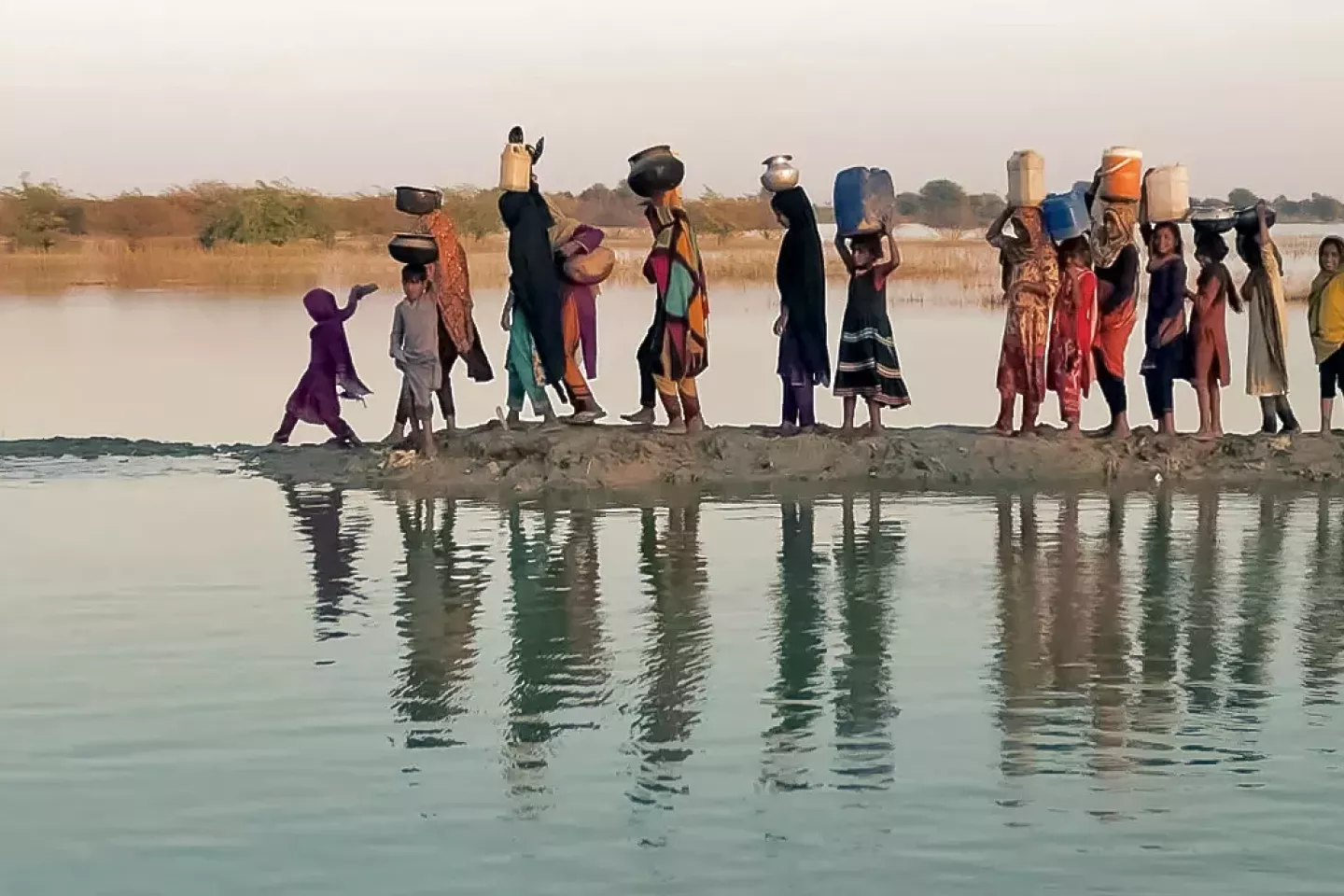 Women and girls walking with their buckets to fetch water in an inundated region of outhern Pakistan.