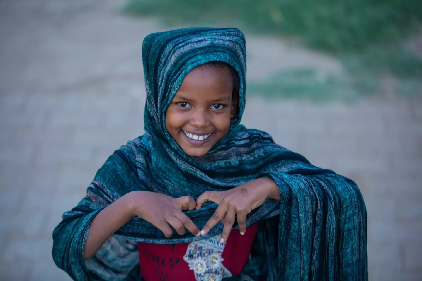 A happy girl showing a sign of hearth meaning love, with her fingers.