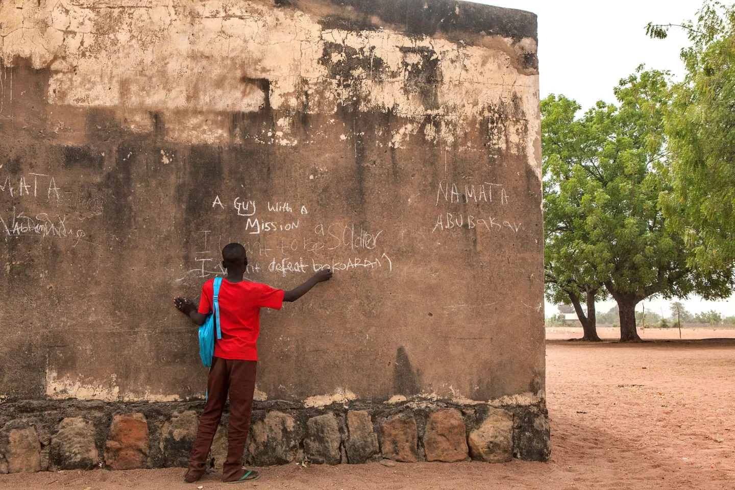 A young boy  writes with chalk on the exterior wall 