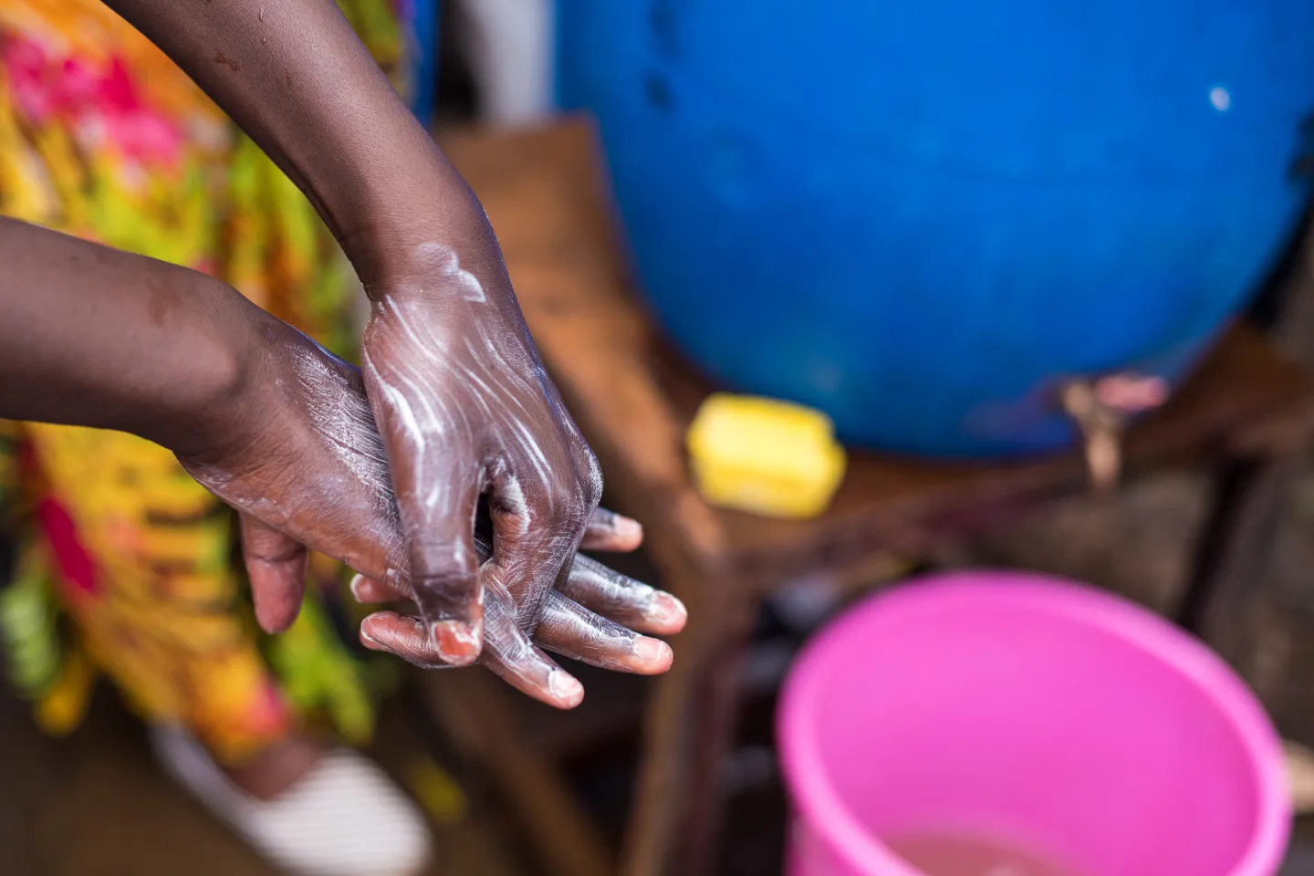 In Nairobi, Kenya, a young boy follows instructions on how to wash hands properly, at a water station in Kibera, to prevent the spread of COVID-19.