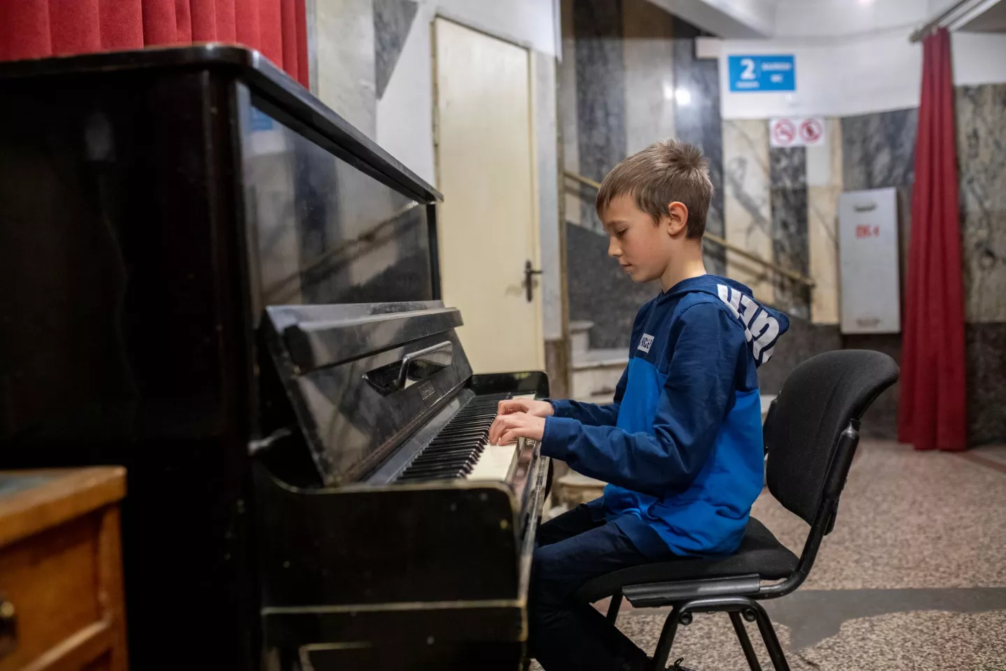 Ukraine. A boy sits at a piano at a theatre.
