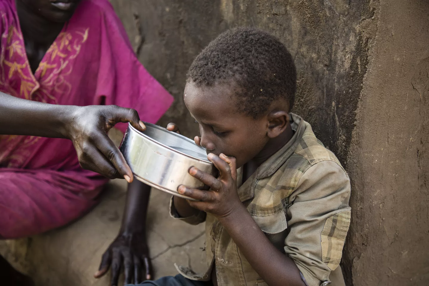 A mother gives water to her son to drink in South Sudan.
