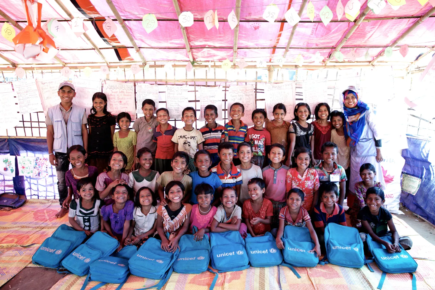 A Bangladeshi teacher and Rohingya refugee children stand in a makeshift classroom at a UNICEF-supported learning centre at the Balukhali makeshift settlement in Ukhia, Cox&rsquo;s Bazar, Bangladesh