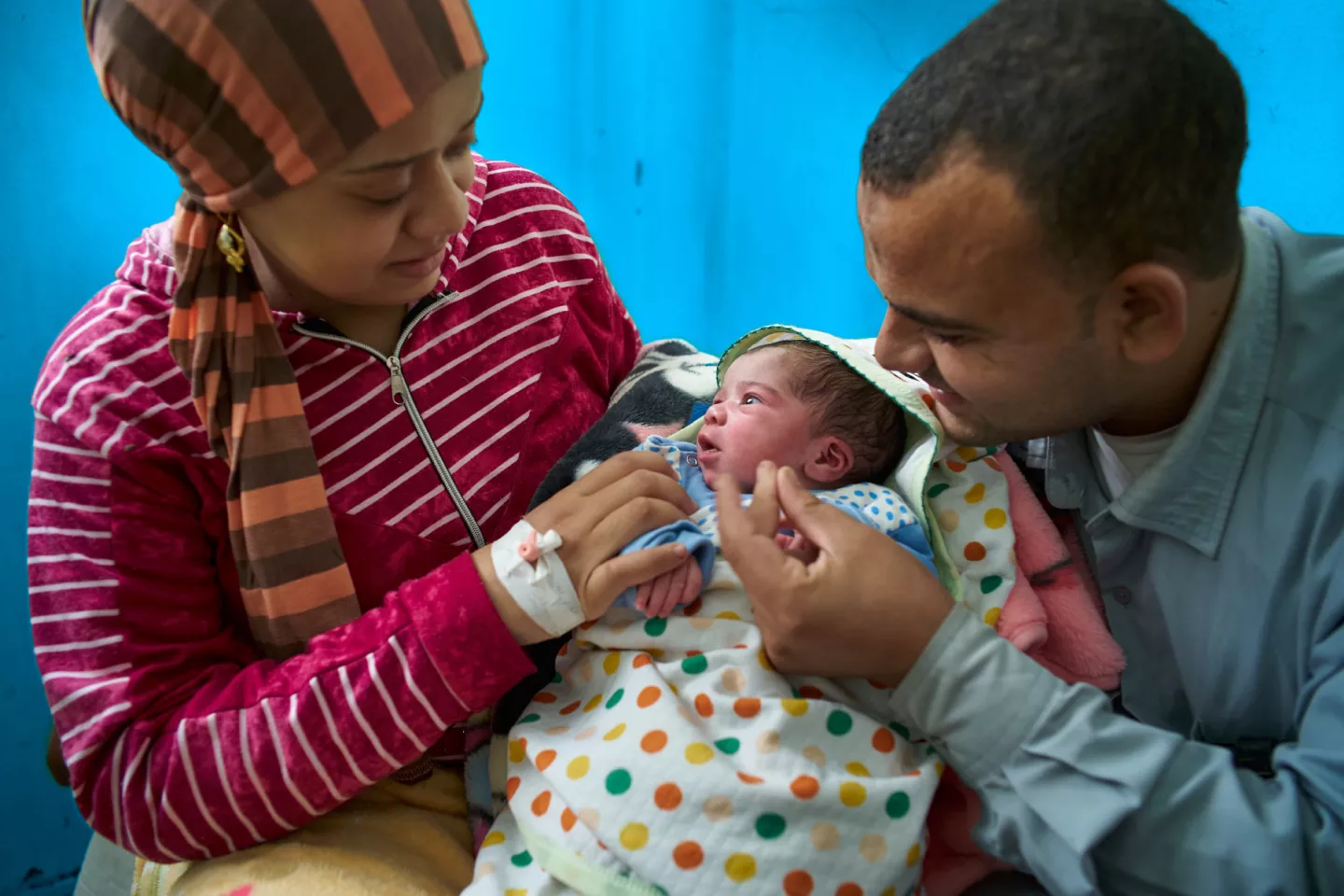 A man and a woman holding their newborn baby swaddled in blankets