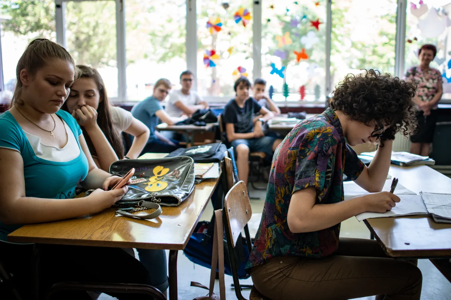 Teenagers sit at desks in a classroom