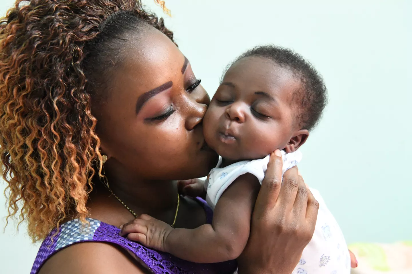 A happy mother gives her baby a kiss on the cheek.