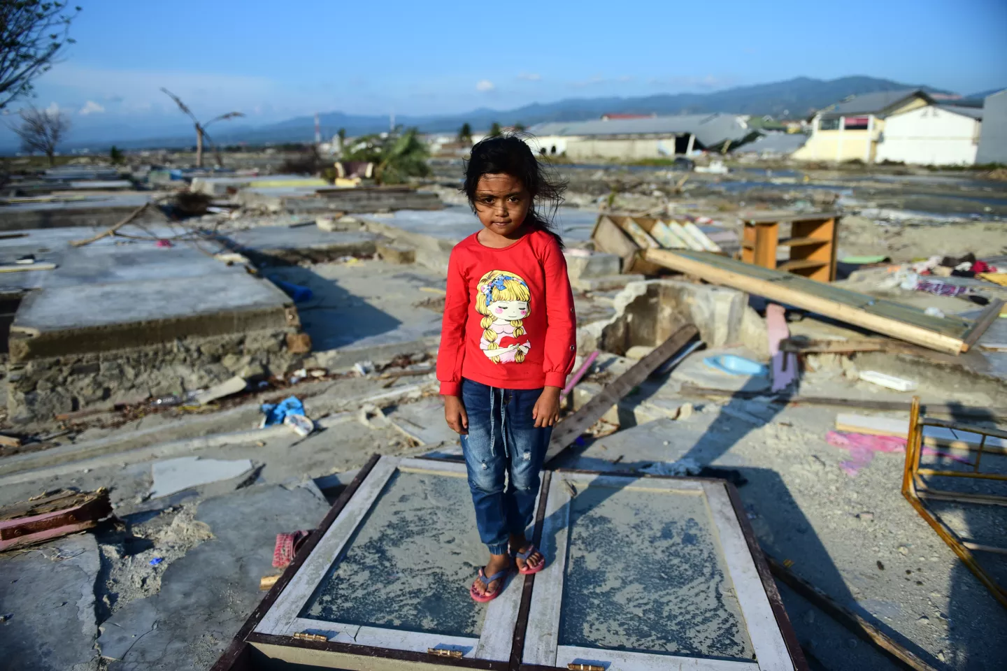 A girl stands among the ruins of her home which was destroyed by the 28 September earthquake and tsunami in Indonesia.