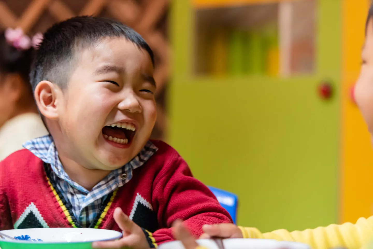 Un ni&ntilde;o de Mongolia come de un cuenco con una enorme sonrisa en su cara en 2018.