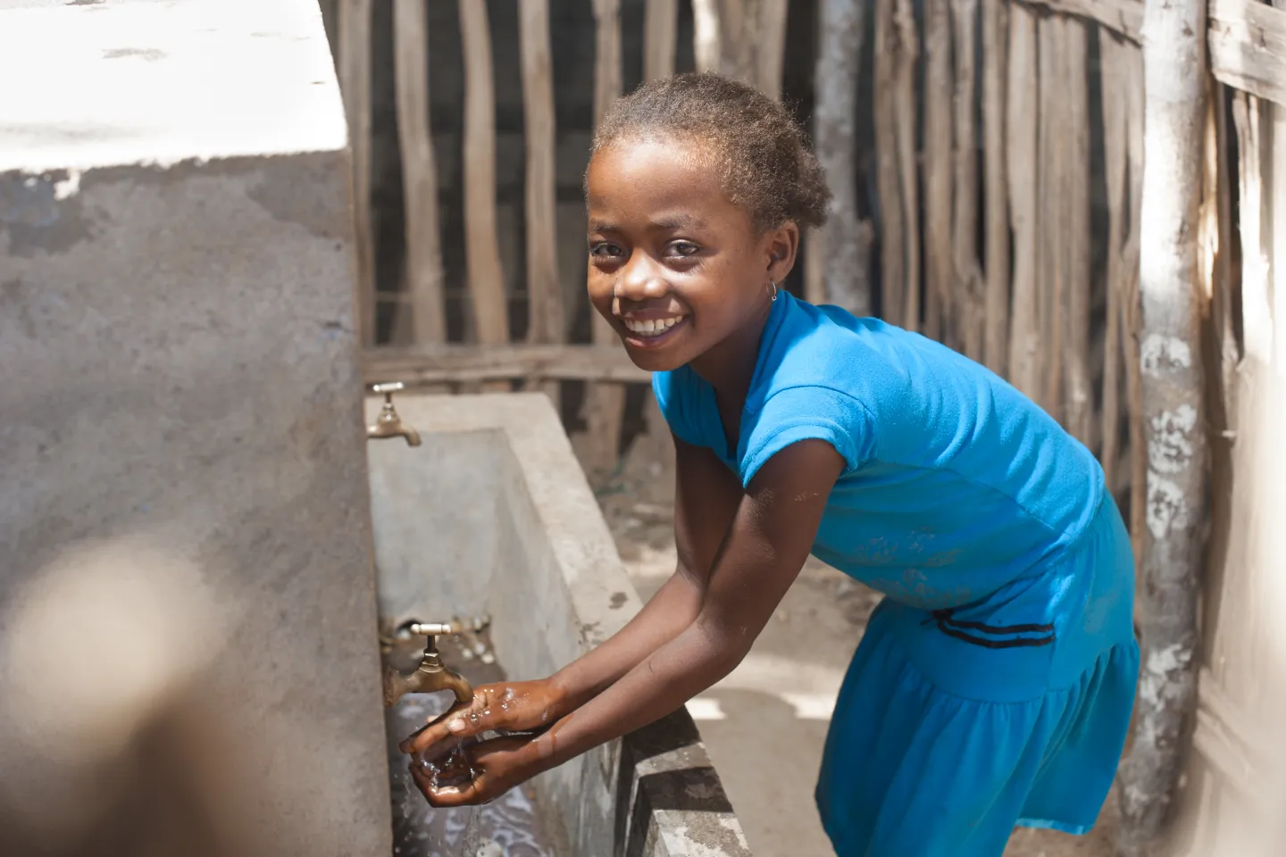 A girl washes her hands at a tap, Madagascar