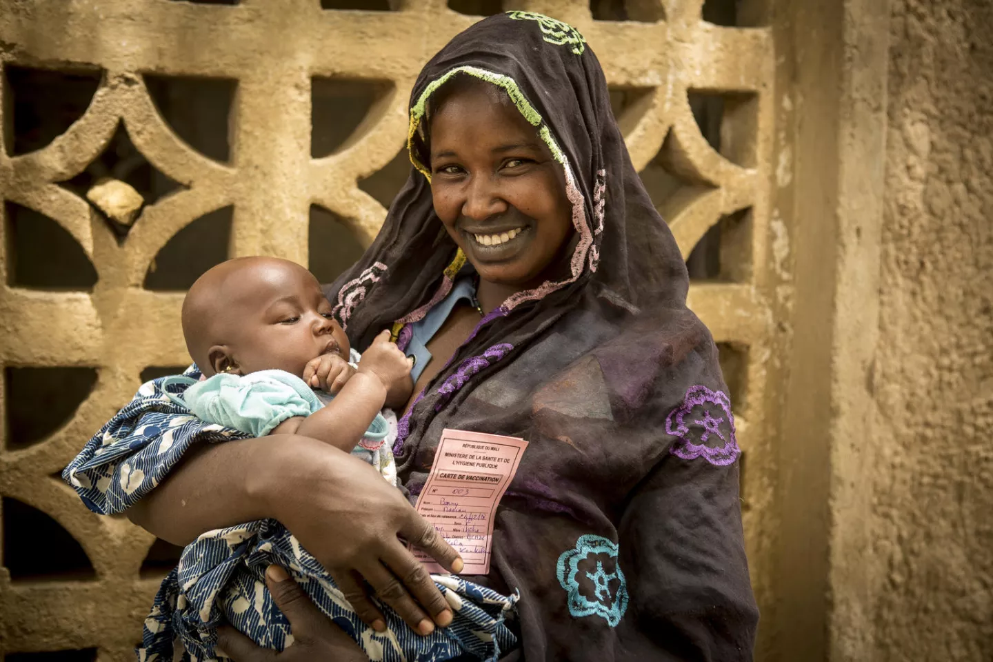 Vaccination in Mali: a mother holds her daughter and a vaccination certificate.