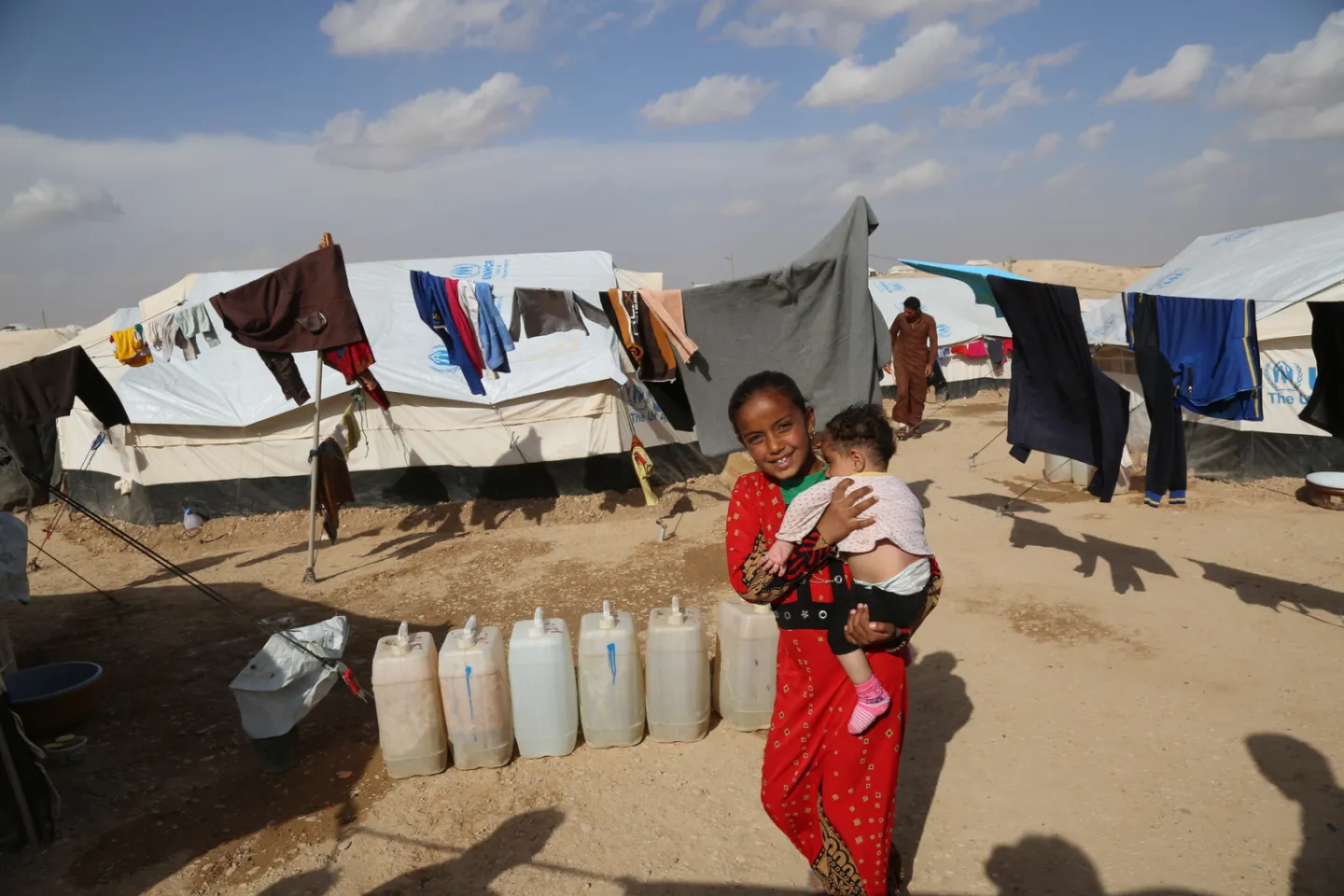 Seven-year-old Manar carries her sibling in the Al Hol camp.