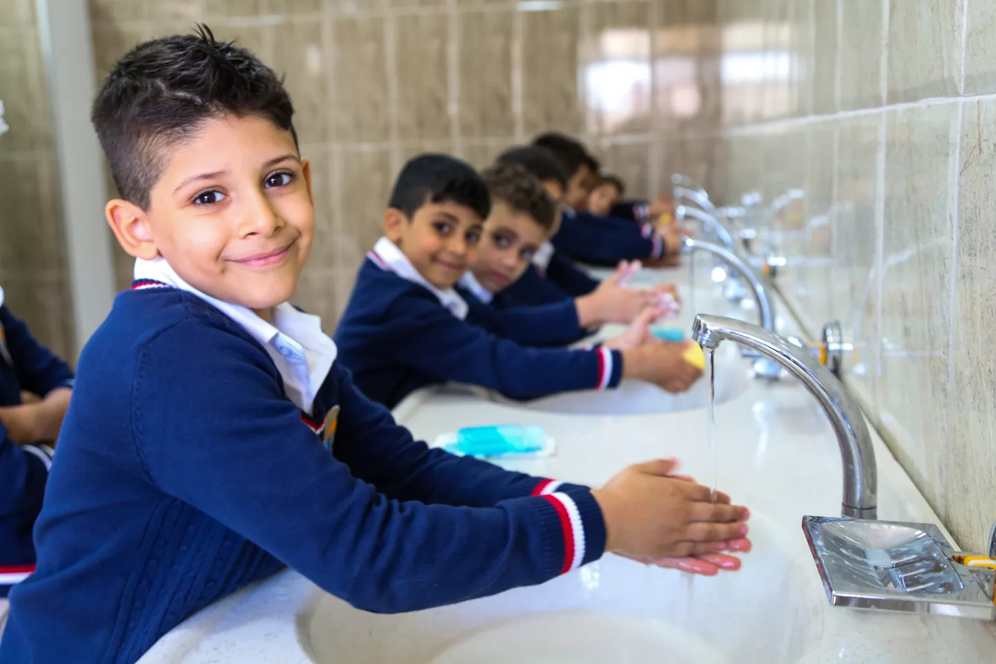Ni&ntilde;os se lavan las manos en una escuela