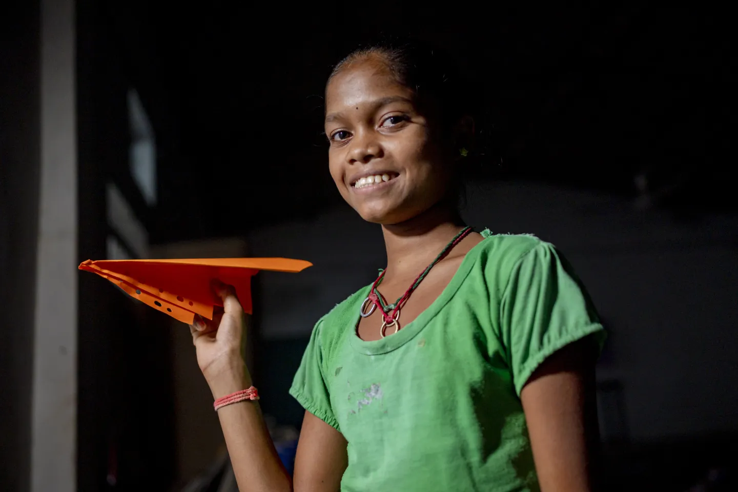 A girl from India, part of a psychosocial support programme for adolescents, holds a paper plan.