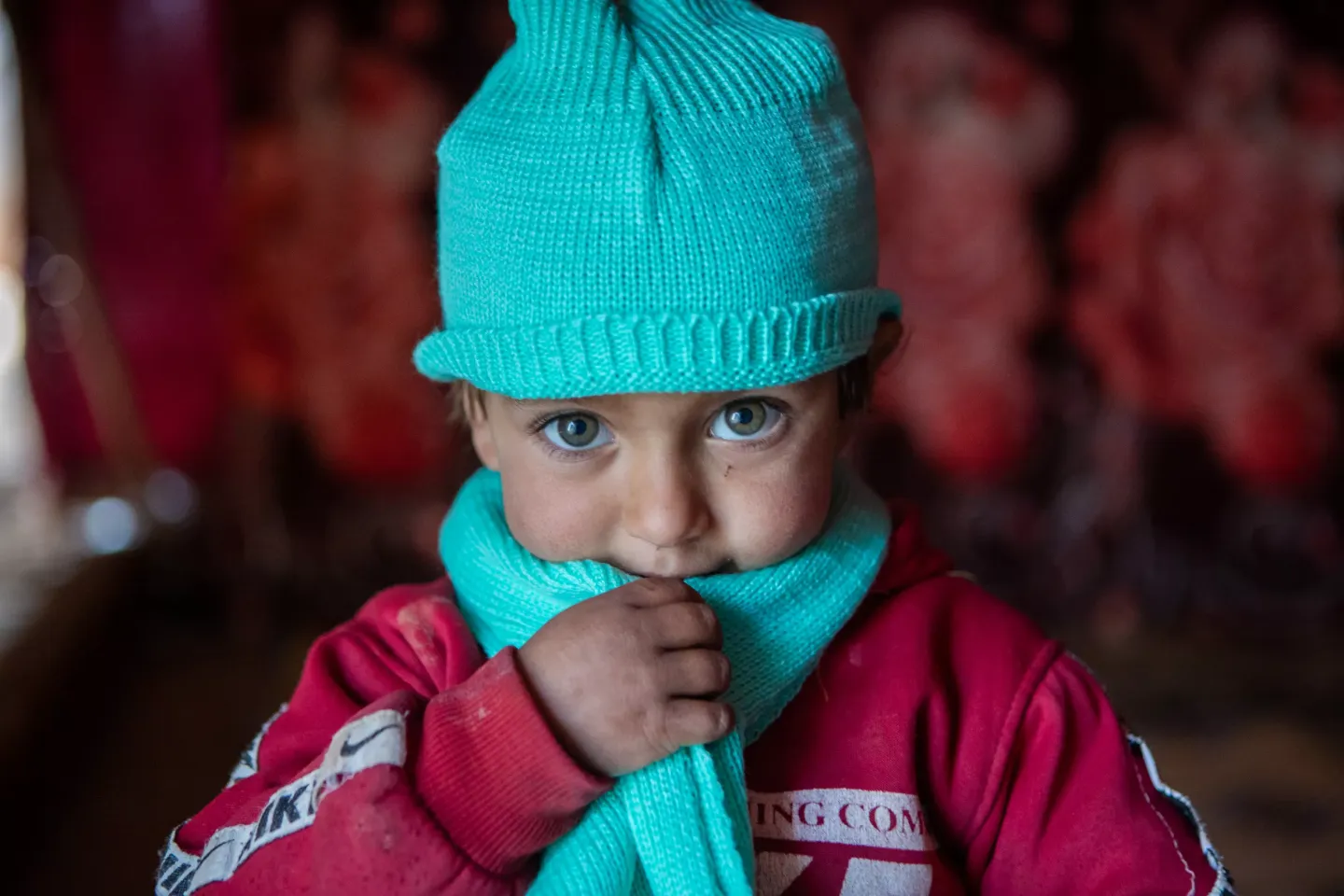 3-year-old Kawthar wears her new woollen hat and scarf, received as part of the winter clothing kits UNICEF distributed in Alzhourieyh makeshift camp, east rural Homs.