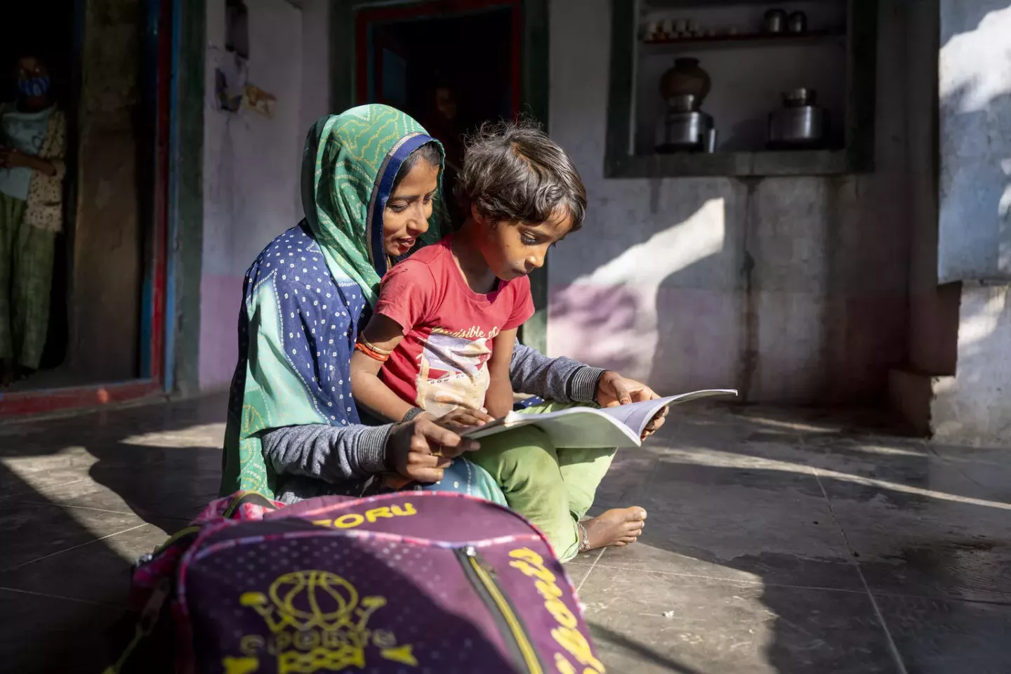 Child sits in mother's lap as they read a book.
