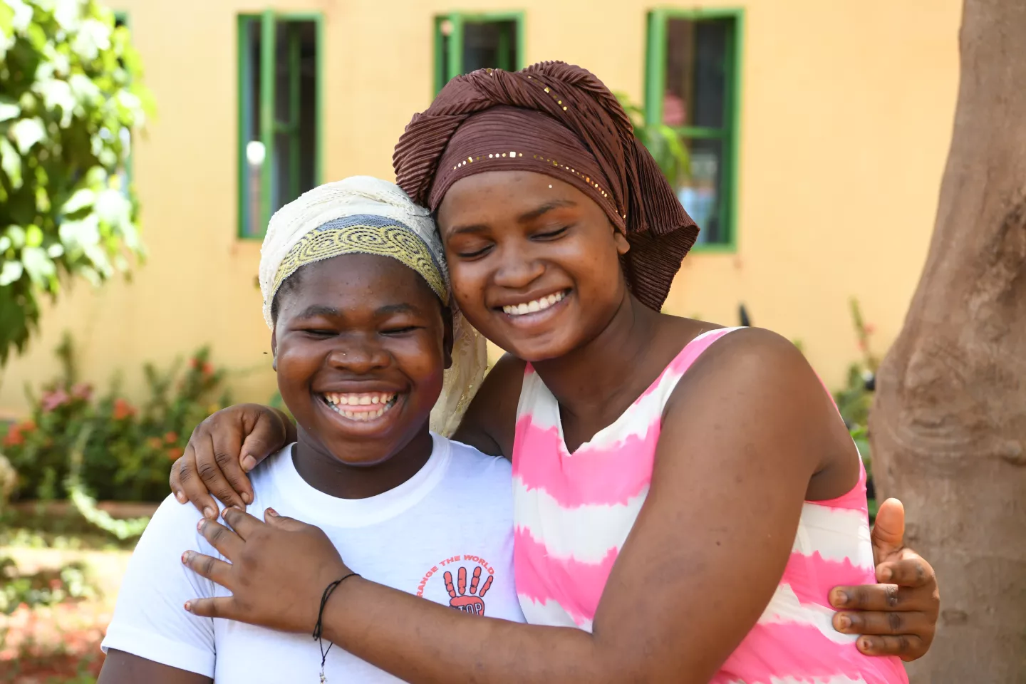 Aminata Sawadogo (derecha), 16, y Sandrine (izquierda), 17, abraz&aacute;ndose y sonriendo en Burkina Faso.