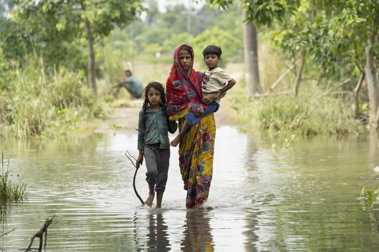 Bangladesh. A woman carries a boy as they walk through floodwaters.