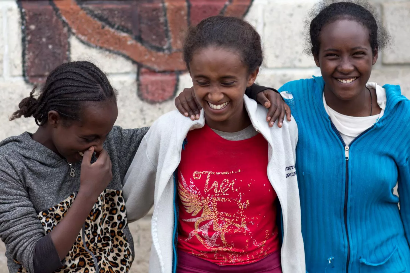 Three girls laugh with their arms around each other, Ethiopia