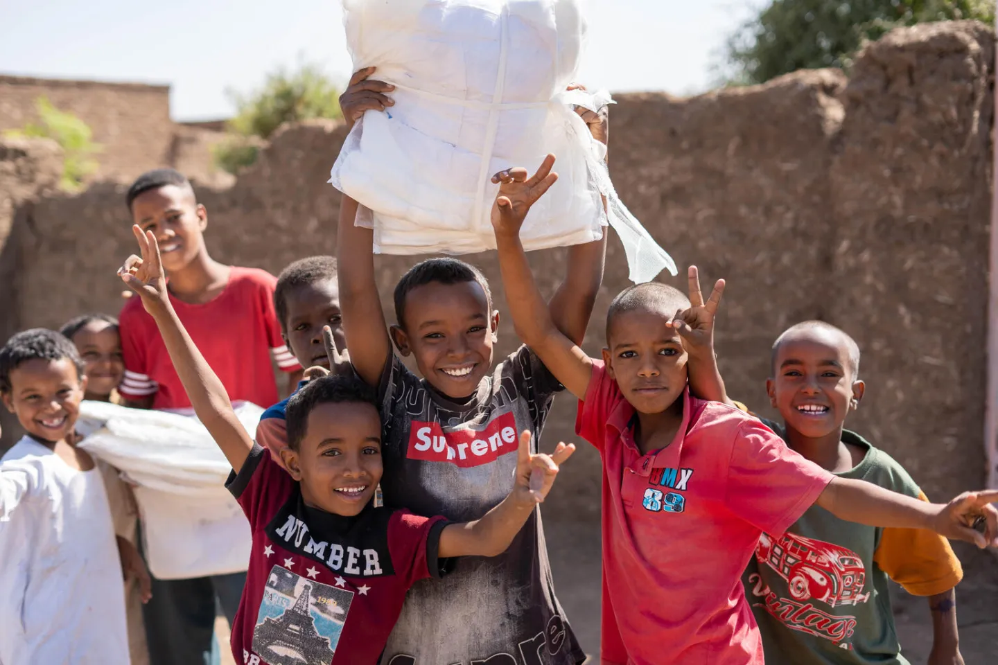 A group of children smiling an lifting mosquito nets.